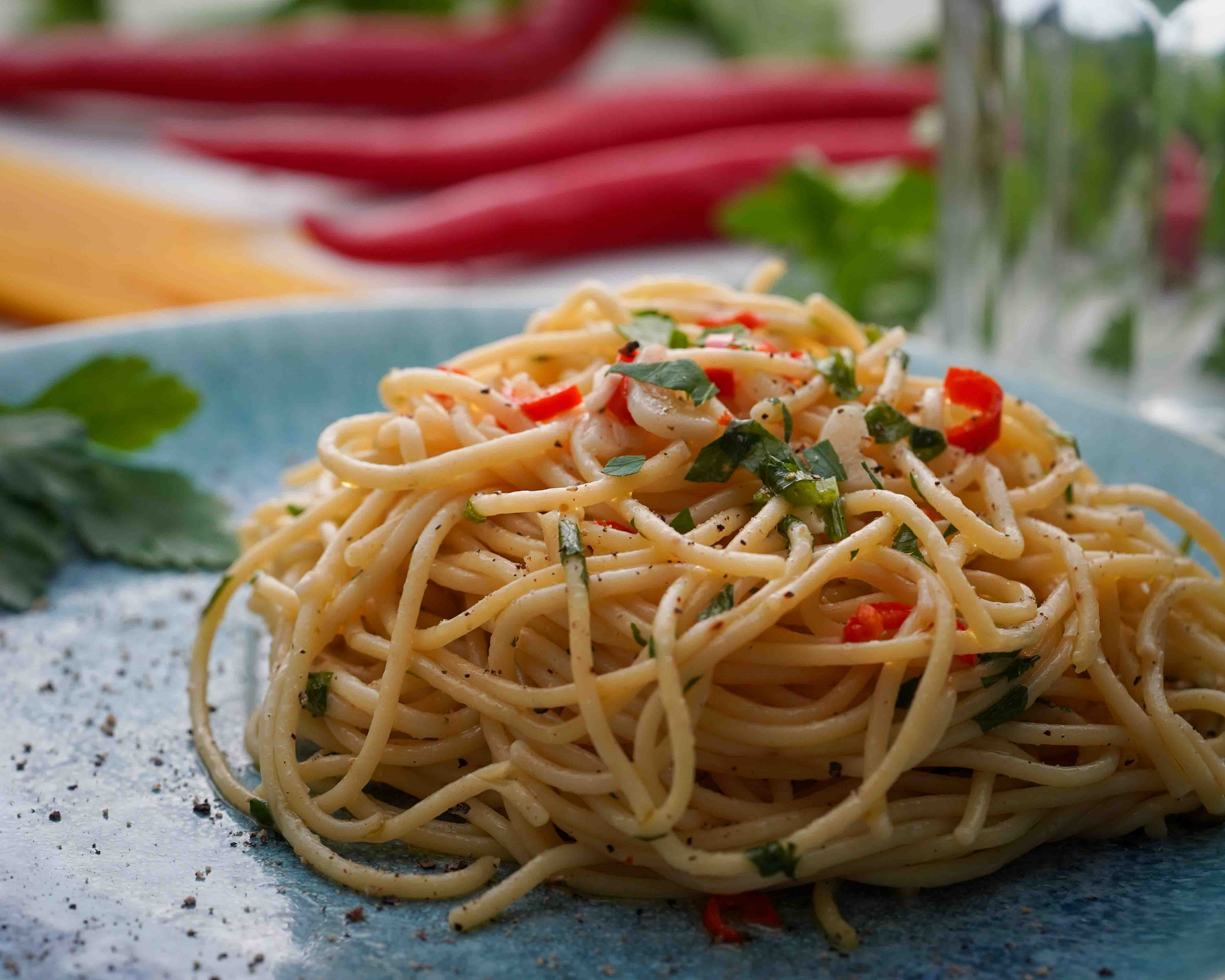 Spaghetti Aglio e olio auf einem bläulichen Teller angerichtet.