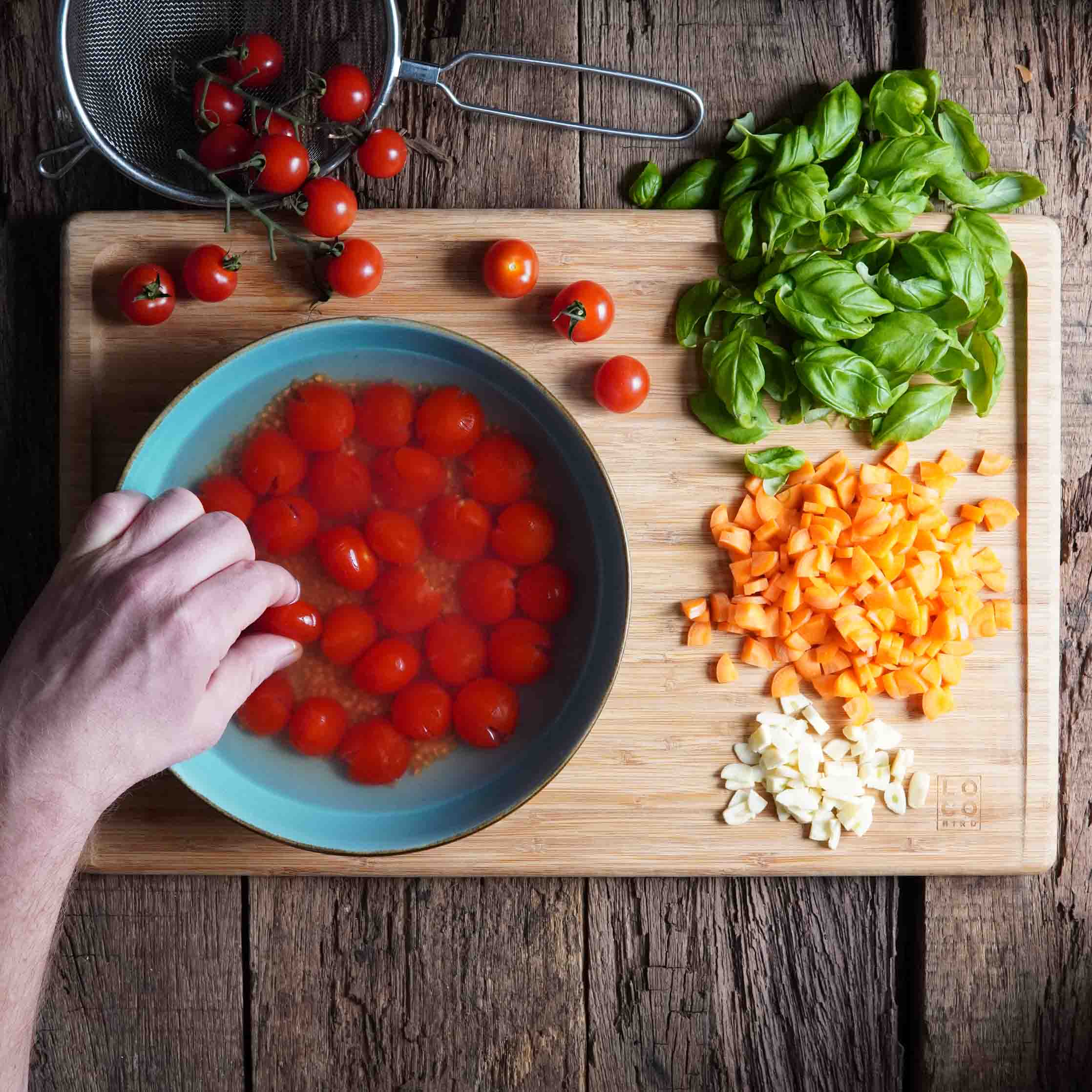 Spaghetti Pomodoro vegan. Schritt 1. Zutaten werden vorbereitet. Mit einer Hand werden Tomaten zerdrückt.