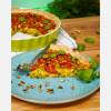 Vegane Quiche auf einem Teller angerichtet, mit Pinienkernen dekoriert, hero