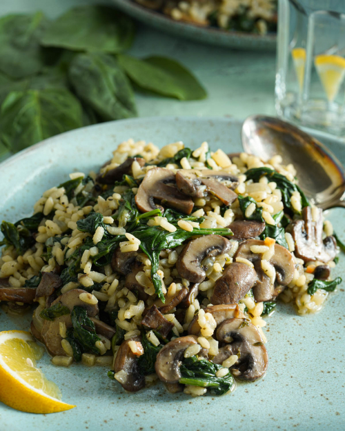 Teller mit veganem Risotto mit Spinat und Champignons